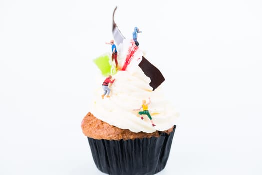 Concept of sugar high or sugar rush with miniature people going up the frosting of cupcake