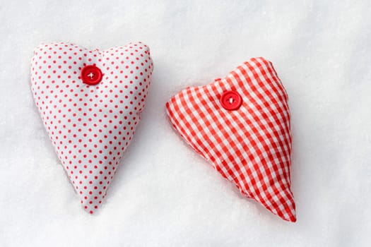 Two red and white hearts made of fabric in the snow