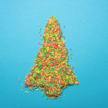 Christmas tree shape of colorful sugar pearls on a blue background