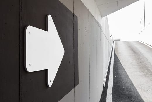White metal arrow on wall. Space for text.