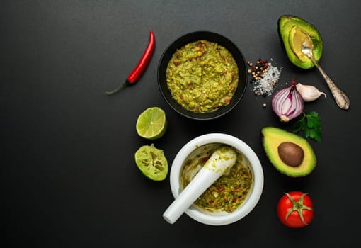 Fresh ingredients with avocado for guacamole sauce on black background