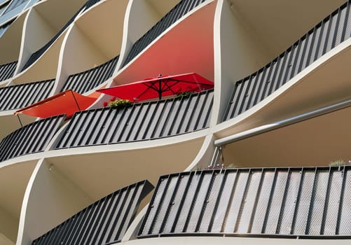 Facade of a modern residential building in the city centre of Magdeburg with two red parasols