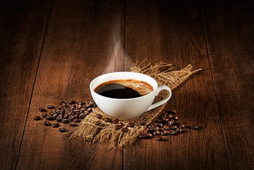 Coffee cup with smoke and beans on wooden table. Copyspace for your text
