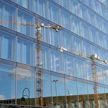 Reflection of a construction crane in the glass façade of an office building in Berlin