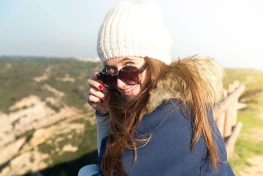 Beautiful happy young girl posing outdoors with sunglasses