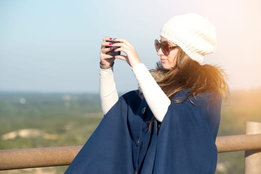 Beautiful happy young girl posing outdoors with phone
