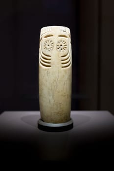 Madrid, Spain - November 10th, 2017: Cylindrical alabaster idol with face depicted. Front view. National Archeological Museum, Madrid
