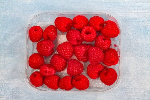 Fresh raspberries on a light blue background