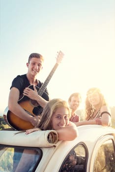 Group of happy people in a car at sunset in summer.