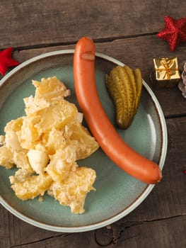 Tasty homemade potato salad with organic sausage and gherkin, traditional Christmas meal
