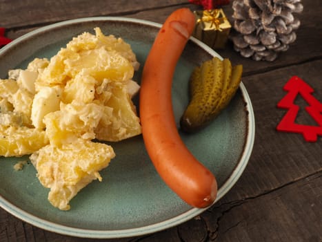Tasty homemade potato salad with organic sausage and gherkin, traditional Christmas meal