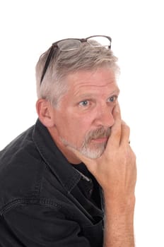 A gray hared middle aged man sitting isolated for white background with.his hand on chin and glasses on his head, isolated for white background.