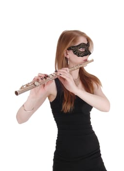 A beautiful young woman standing, playing her flute and.wearing a mask over her eyes in a black dress, isolated over white.