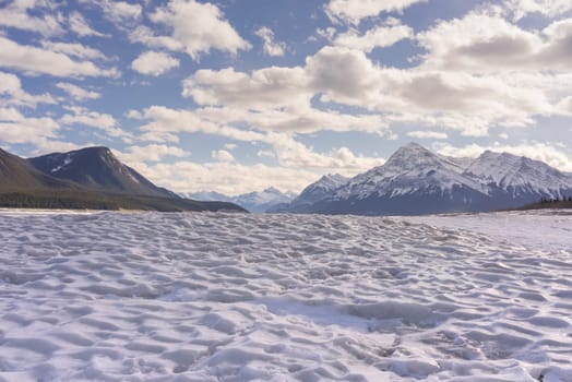 Landscape of the textured ice of Abraham Lake with mountains in the background, Alberta, Canada.