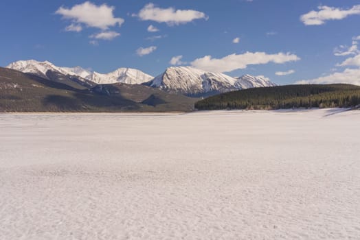 Abraham Lake covered in snow with mountains in the background, Alberta, Canada.