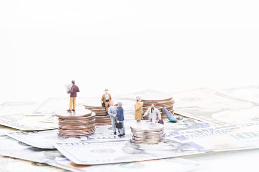 Miniature business people on coins and banknotes