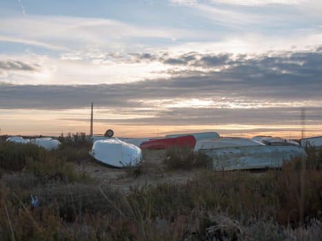 row of upturned beach boats flat on land with dramatic sun set sky tourism  west mersea, essex, england, uk