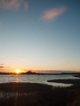 sun setting horizon blue water sky surface silhouette coast ocean waves  essex  england  uk