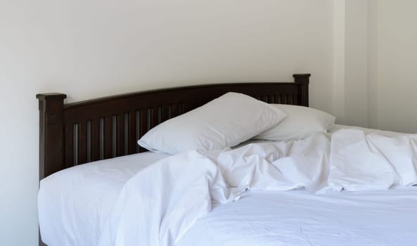 Morning view of an unmade bed in white bedroom