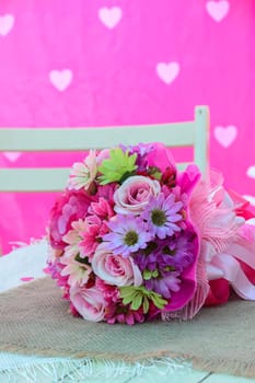 Artificial bouquet flowers on white table with pink background. Valentine concept image.