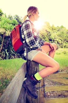 Beautiful blond hiking woman resting on gate