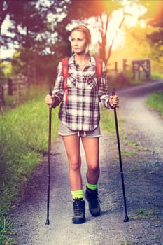 Beautiful young woman hiking with poles