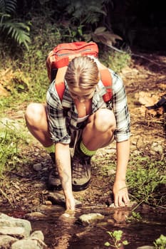 Hiking woman drinking from stream