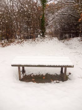 wooden covered public bench snow outside winter grass covered white  essex  england  uk
