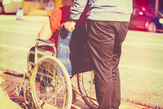 Woman in wheelchair with man pushing