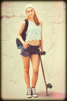 Teen skater girl standing with skateboard
