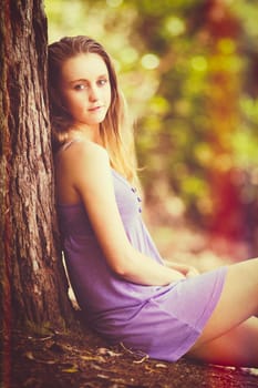 Pretty girl sitting by tree