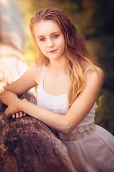 Beautiful teenage girl posing by log