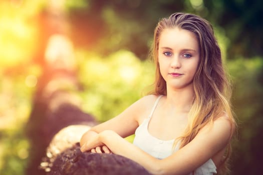 Beautiful young teenage woman by fallen tree