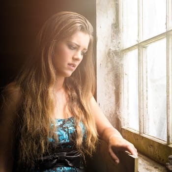 Sad young woman by window