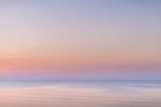 Horizontal picture of clouds in the sky above calm sea surface during sunset
