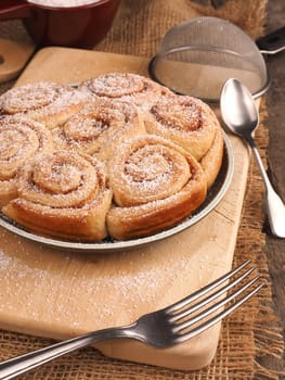 Homemade cinnamon snails with kitchen utensils on a rustic wooden kitchen table
