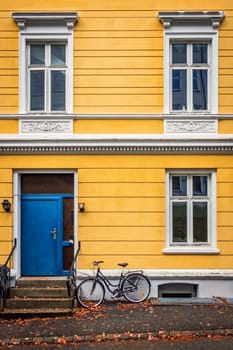 Old vintage bicycle parked under the windows of an old yellow house in the Bergen old town, Norway