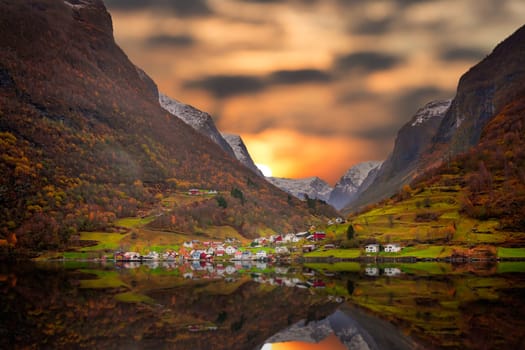 Small homes on the shore of a fjord photographed from a Fjords sightseeing cruise boat leaving Flam in autumn, Norway