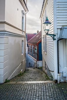 Narrow cobble stoned streets between old white traditional houses in the old part of Bergen town, Norway