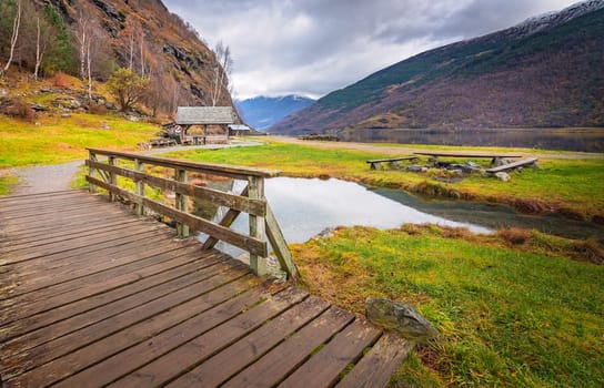 Small wooden bridge on a path leading to the fjord shore in small village Flam, Norway
