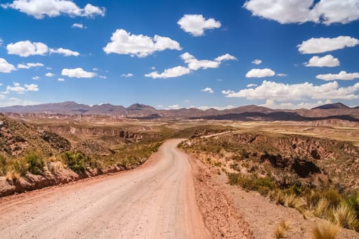 Empty and dusty gravel desert road through remote part of central Bolivia