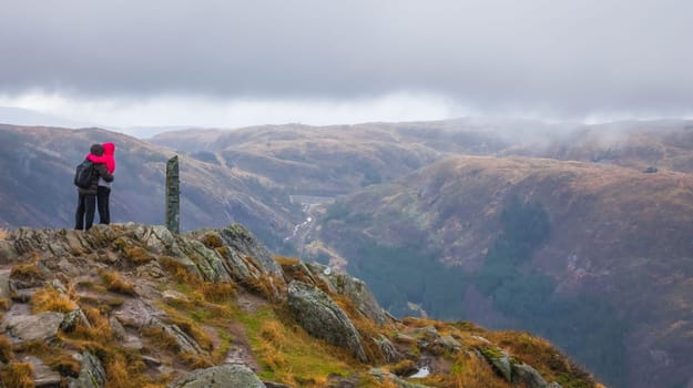 Unidentifiable tourists standing on the top of mount Ulriken in Bergen in loving embrace, Norway