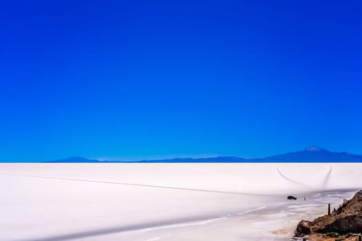 Four wheel car with touriusts in front of the Cactus island in the middle of Salar de Uyuni in Bolivia