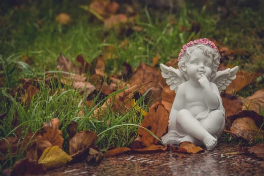 Tiny angel figure next to a child grave in cemetery