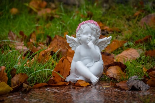 Tiny angel figure next to a child grave in cemetery