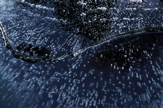 A chunk of ice with frozen air bubbles in the water. A small iceberg in the water