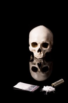 cocaine, Herion or other illegal drugs that are sniffed by means of a tube or injected with a syringe, money and Skull, isolated on black glossy background