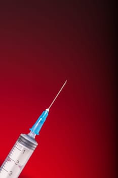 Isolated medical syringe on red, dark background