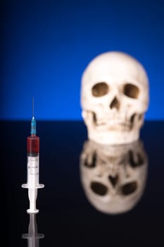 Blurry Skull and syringe, isolated on black blue background with glossy reflection