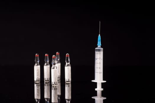 syringe and medical vials isolated on black background